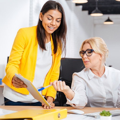 Two women discussing information on papers